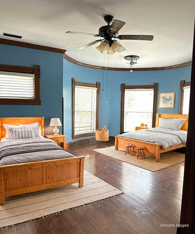 bedroom featuring wood finished floors, visible vents, crown molding, and a ceiling fan