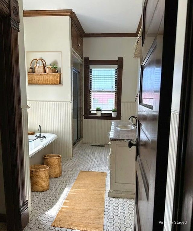 full bathroom featuring a freestanding bath, a stall shower, wainscoting, vanity, and ornamental molding