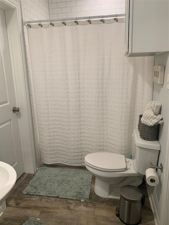 full bathroom with toilet, a shower with curtain, and wood finished floors