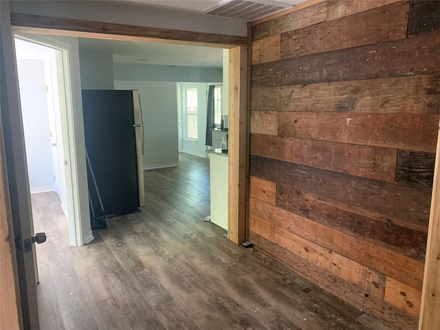hall featuring wooden walls, visible vents, baseboards, and wood finished floors