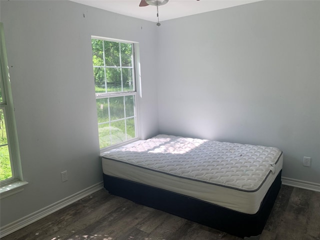 bedroom with dark wood finished floors, baseboards, and multiple windows