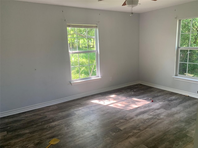 empty room featuring dark wood-type flooring, ceiling fan, baseboards, and plenty of natural light