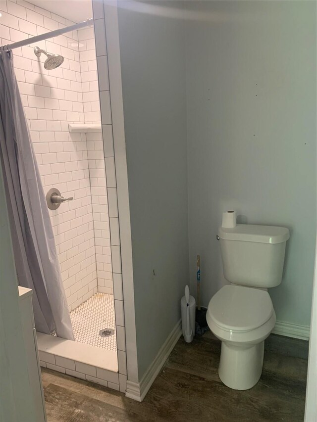 bathroom featuring a shower stall, baseboards, toilet, and wood finished floors