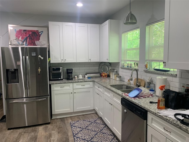kitchen with a sink, white cabinets, appliances with stainless steel finishes, and decorative backsplash