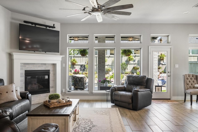 living area with a glass covered fireplace, recessed lighting, visible vents, ceiling fan, and wood finished floors