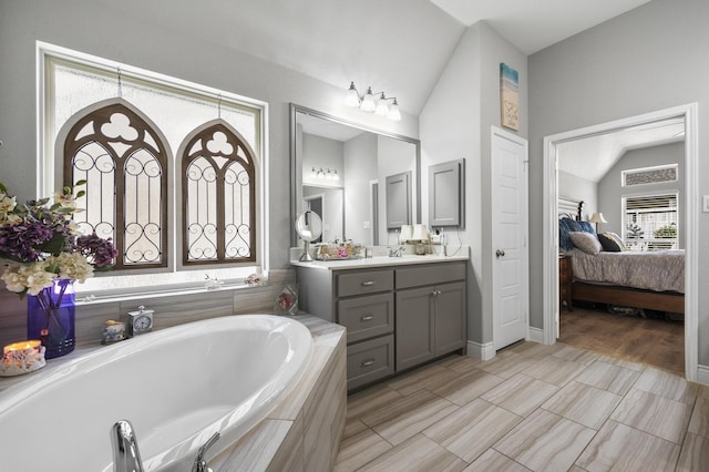 full bathroom featuring vanity, a bath, connected bathroom, and lofted ceiling