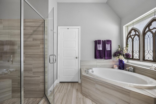 bathroom with a bath, a stall shower, and lofted ceiling