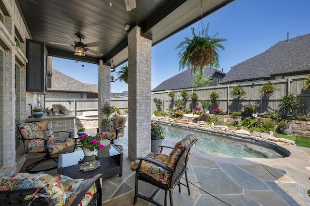 view of patio featuring a fenced backyard, ceiling fan, exterior kitchen, and a hot tub
