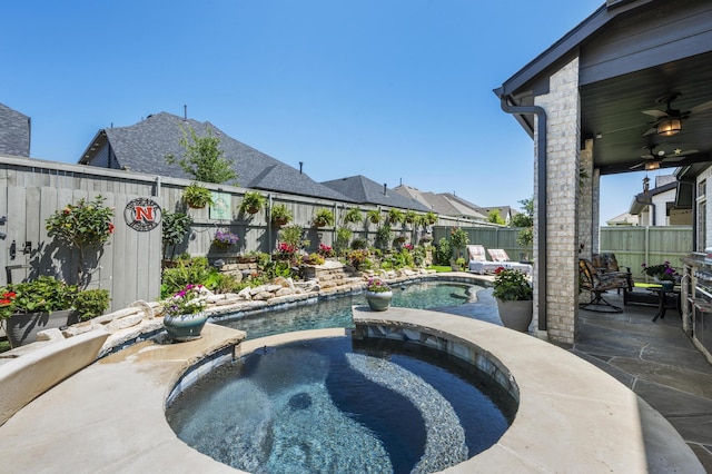 view of pool featuring a fenced backyard, ceiling fan, a pool with connected hot tub, and a patio
