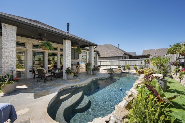 view of swimming pool featuring a patio area, ceiling fan, a pool with connected hot tub, a fenced backyard, and an outdoor kitchen