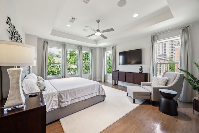 3912 Holland Ave, Dallas, TX 75219 - bedroom with a raised ceiling, multiple windows, wood finished floors, recessed lighting, and a ceiling fan