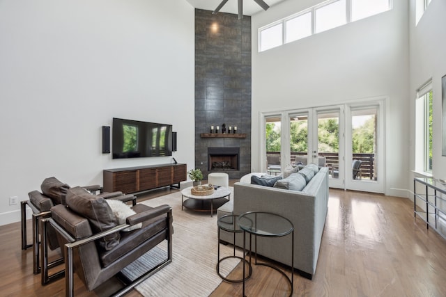 3912 Holland Ave, Dallas, TX 75219 - living area with a towering ceiling, a large fireplace, ceiling fan, wood finished floors, and baseboards