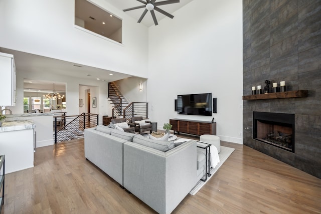 3912 Holland Ave, Dallas, TX 75219 - living area with a fireplace, light wood-type flooring, a ceiling fan, stairway, and a chandelier