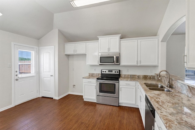 kitchen featuring appliances with stainless steel finishes, lofted ceiling, dark wood finished floors, arched walkways, and a sink