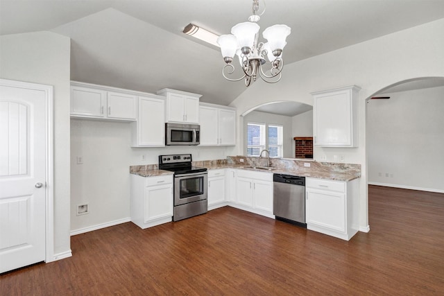 kitchen featuring arched walkways, white cabinets, vaulted ceiling, a sink, and stainless steel appliances