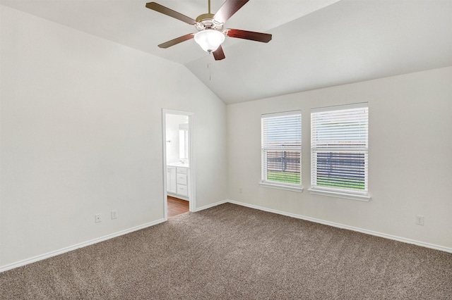 spare room featuring carpet flooring, baseboards, vaulted ceiling, and a ceiling fan