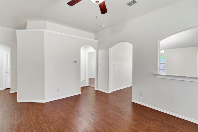 empty room featuring visible vents, baseboards, arched walkways, ceiling fan, and wood finished floors