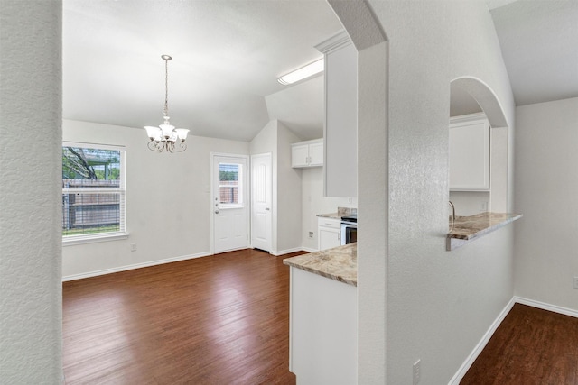 kitchen with dark wood-style flooring, vaulted ceiling, light stone counters, white cabinets, and arched walkways