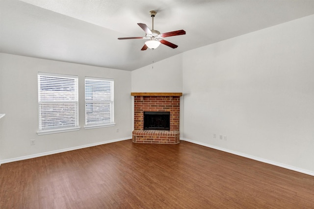 unfurnished living room featuring baseboards, a ceiling fan, a brick fireplace, lofted ceiling, and wood finished floors
