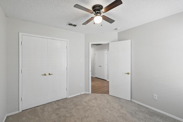 unfurnished bedroom with a textured ceiling, a closet, visible vents, and carpet