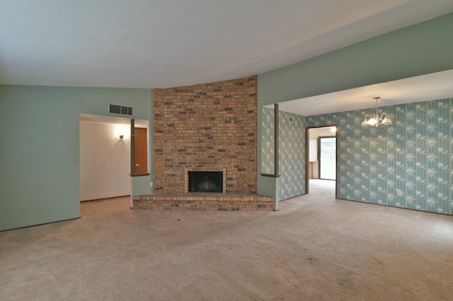 unfurnished living room with visible vents, carpet flooring, an inviting chandelier, and a fireplace