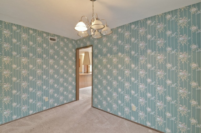 carpeted spare room with wallpapered walls, a notable chandelier, and visible vents