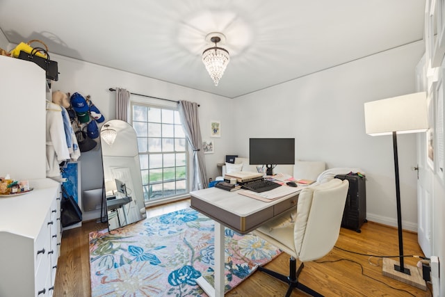 home office with wood finished floors and a notable chandelier