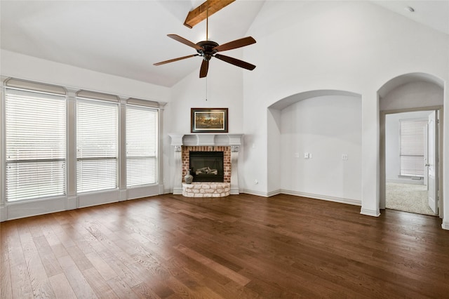 unfurnished living room featuring ceiling fan, arched walkways, a brick fireplace, high vaulted ceiling, and dark wood-type flooring