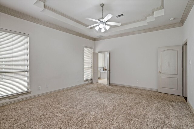 empty room with visible vents, ornamental molding, a raised ceiling, and plenty of natural light