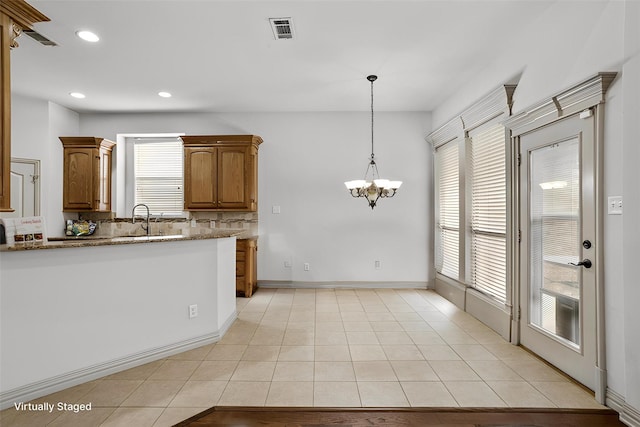 7816 Shady Oaks Dr, North Richland Hills, TX 76182 - kitchen featuring a sink, a chandelier, tasteful backsplash, brown cabinets, and light stone counters