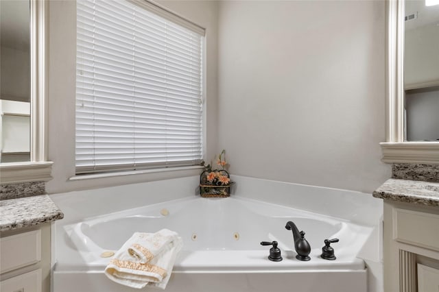 full bathroom featuring vanity, a whirlpool tub, and visible vents