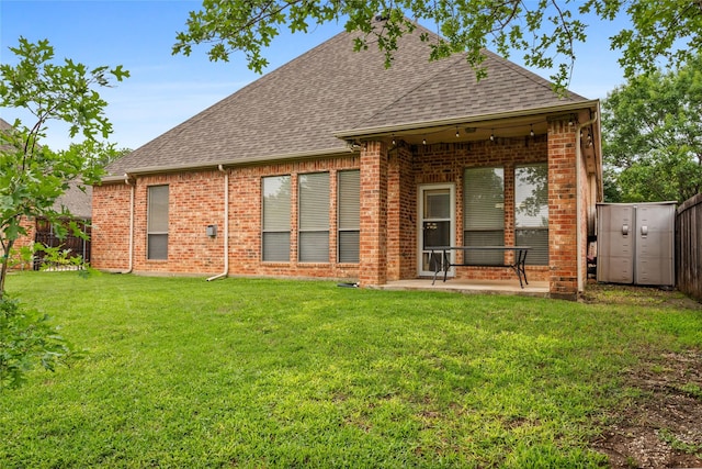 back of house featuring a fenced backyard, a patio, a shingled roof, and brick siding