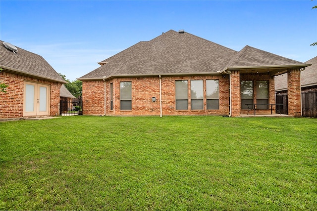 back of property with a lawn, a fenced backyard, roof with shingles, and brick siding