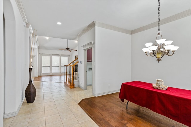 dining space featuring light tile patterned flooring, ceiling fan with notable chandelier, baseboards, ornamental molding, and stairway