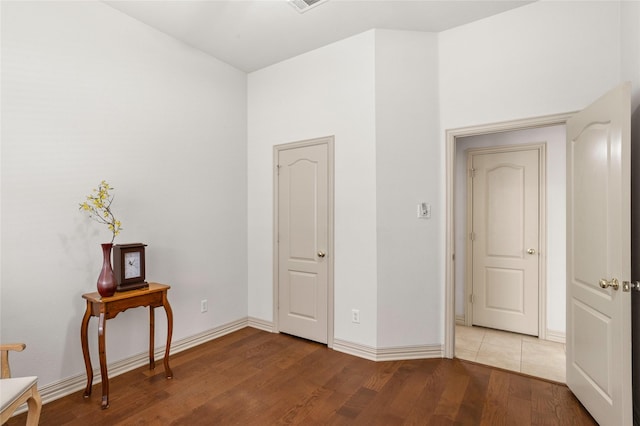 unfurnished bedroom with baseboards, wood finished floors, and visible vents