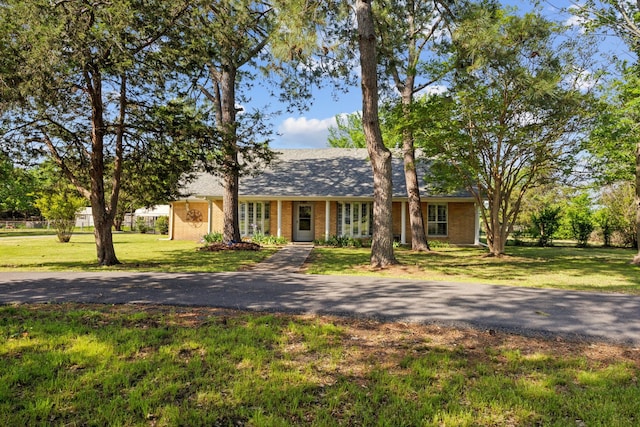 ranch-style home featuring a front yard, brick siding, and roof with shingles