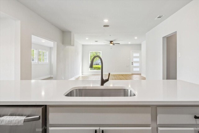 kitchen with dishwasher, a sink, open floor plan, light countertops, and recessed lighting