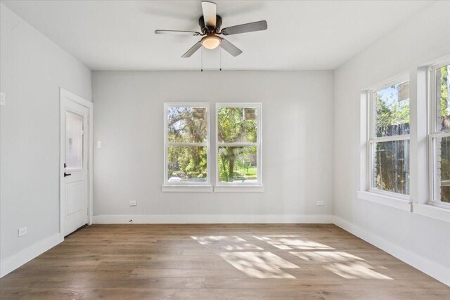 unfurnished room featuring a wealth of natural light, ceiling fan, and wood finished floors