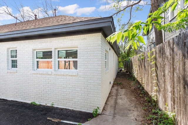 view of side of property with brick siding and fence