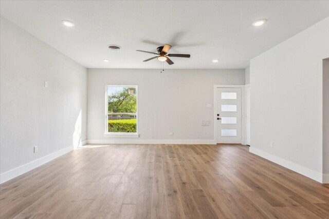 empty room featuring a healthy amount of sunlight, light wood finished floors, visible vents, and ceiling fan