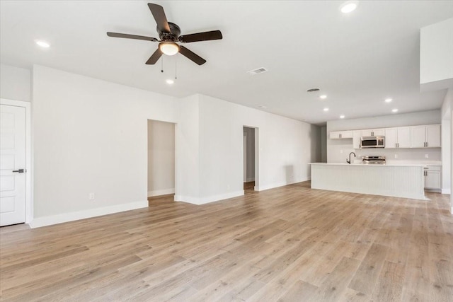 unfurnished living room featuring light wood-style flooring, a sink, visible vents, and recessed lighting
