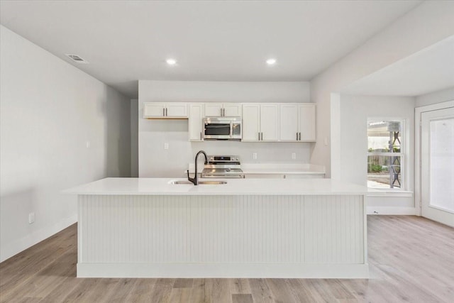 kitchen featuring light wood-type flooring, light countertops, visible vents, appliances with stainless steel finishes, and a sink