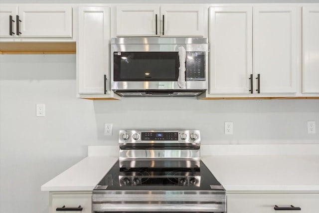 kitchen with stainless steel appliances, light countertops, and white cabinetry