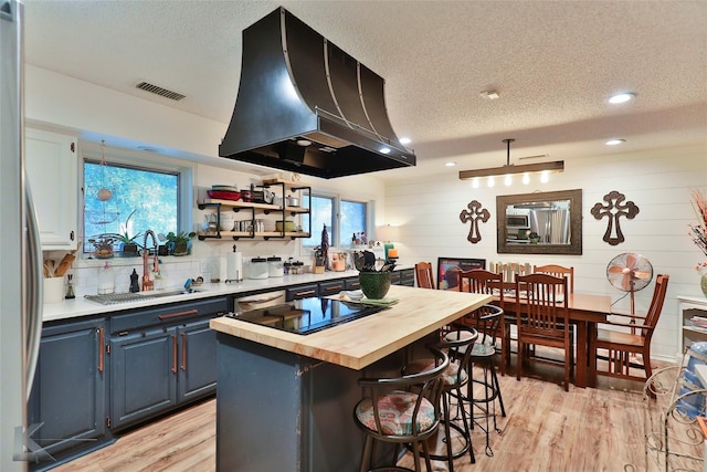 1929 S 13th St, Abilene, TX 79602 - kitchen featuring visible vents, wall chimney exhaust hood, a textured ceiling, and wooden counters