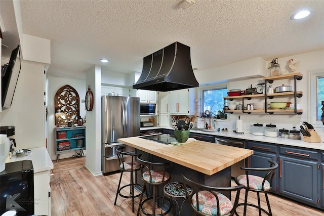 1929 S 13th St, Abilene, TX 79602 - kitchen featuring a breakfast bar, a textured ceiling, exhaust hood, wooden counters, and stainless steel appliances