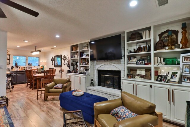 1929 S 13th St, Abilene, TX 79602 - living room featuring a brick fireplace, visible vents, a textured ceiling, and light wood-style flooring
