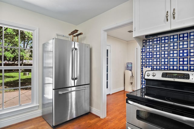 kitchen with white cabinets, baseboards, wood finished floors, and stainless steel appliances