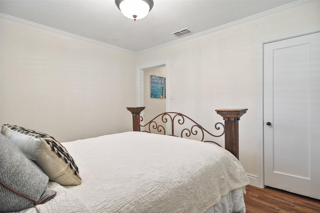 bedroom with visible vents, a textured ceiling, ornamental molding, and dark wood-style floors