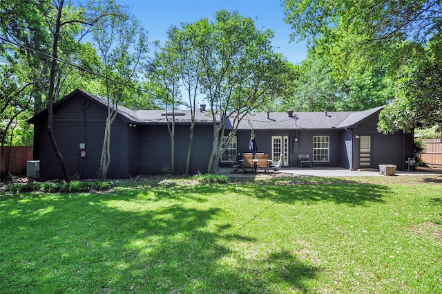 rear view of property with cooling unit, a patio, fence, and a lawn