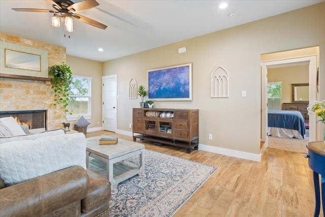 living area with baseboards, ceiling fan, and light wood finished floors